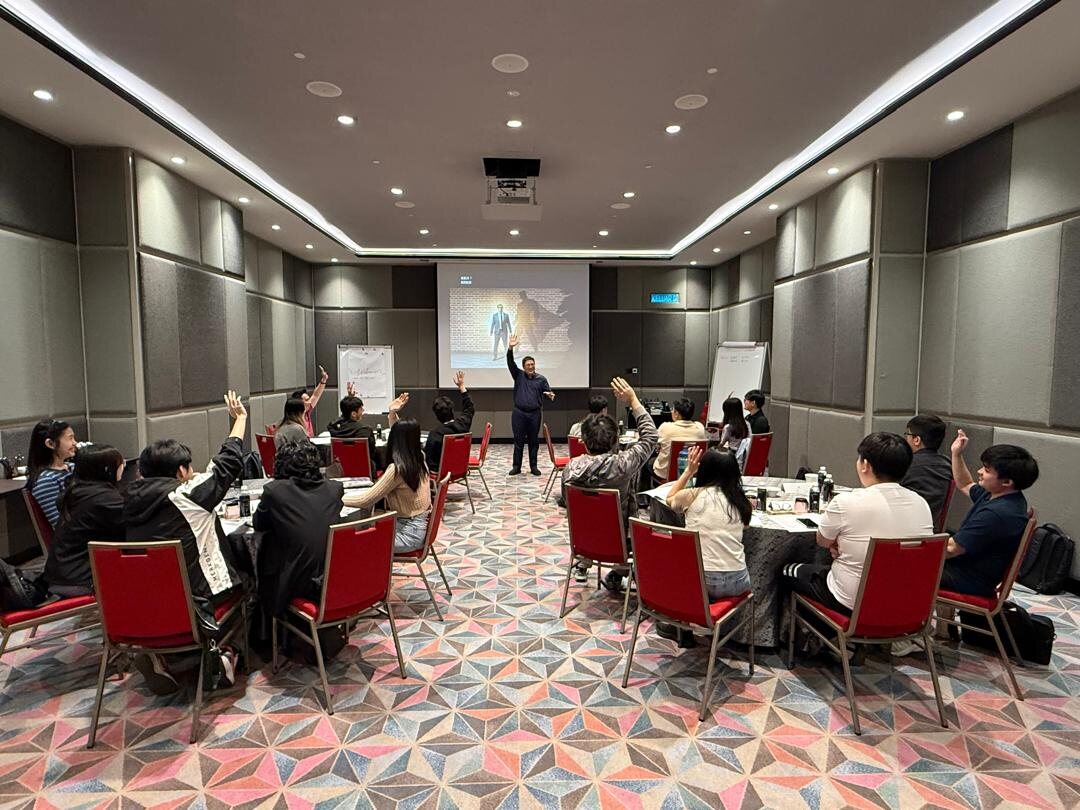 Soo Hoo facilitating a leadership room with participants raising their hands